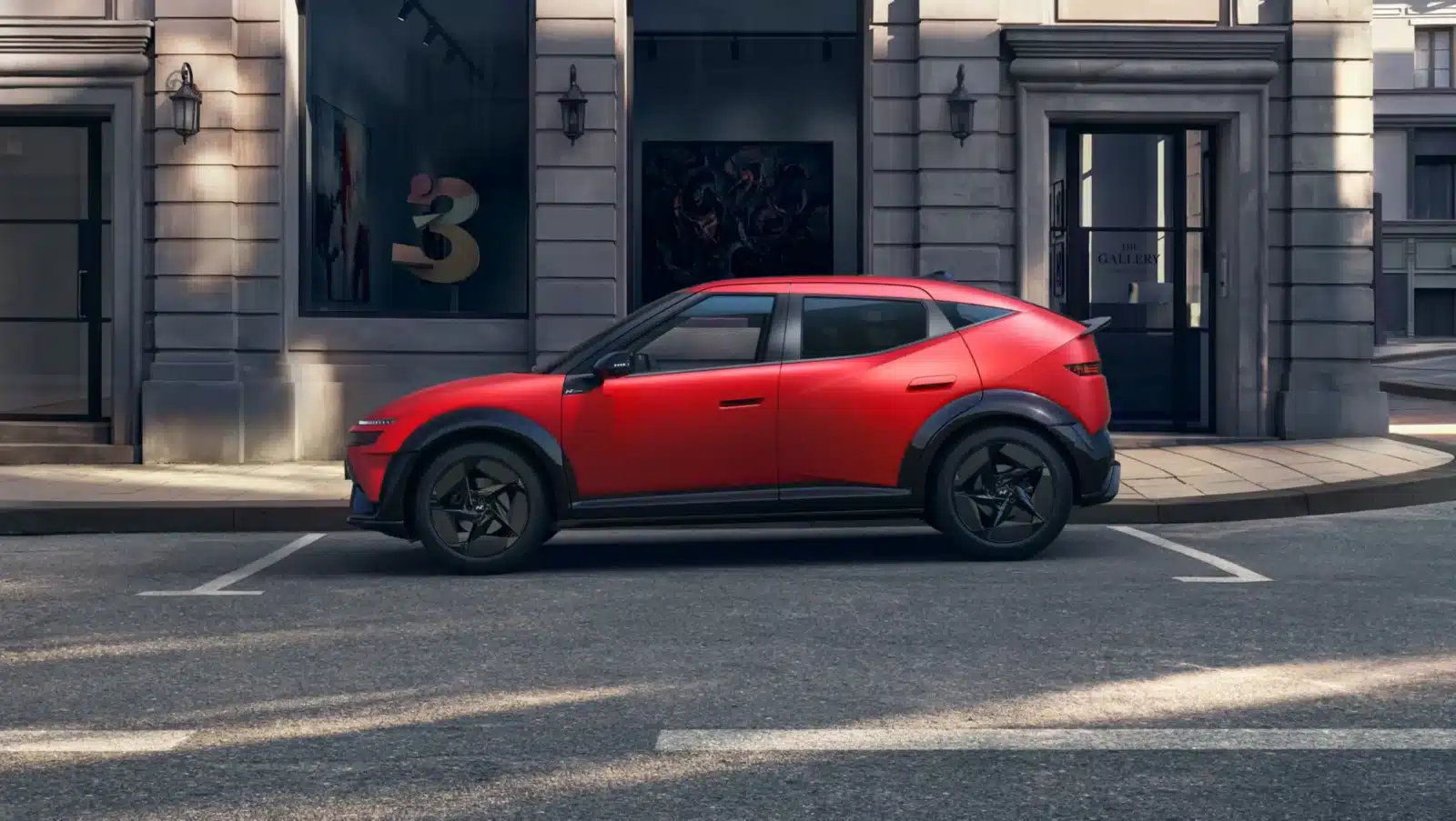 Ein roter, moderner Kompakt-Geländewagen parkt auf einer Straße in der Stadt vor einem Steingebäude mit großen Fenstern, auf denen Kunstwerke und die Zahl 3 zu sehen sind.