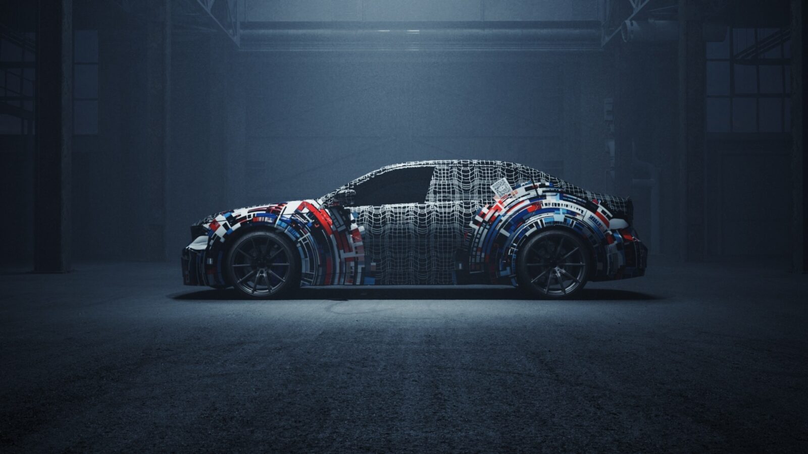 Seitenansicht eines mit einer Tarnfolie mit geometrischen Mustern und Farben beklebten Autos, das in einer schwach beleuchteten Industriegarage geparkt ist. Die Designdetails des Fahrzeugs sind durch die Folie verdeckt.